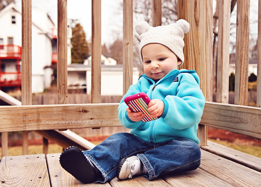 12 month old Lila playing with a cell phone, taken by MA photographer Megan Moore